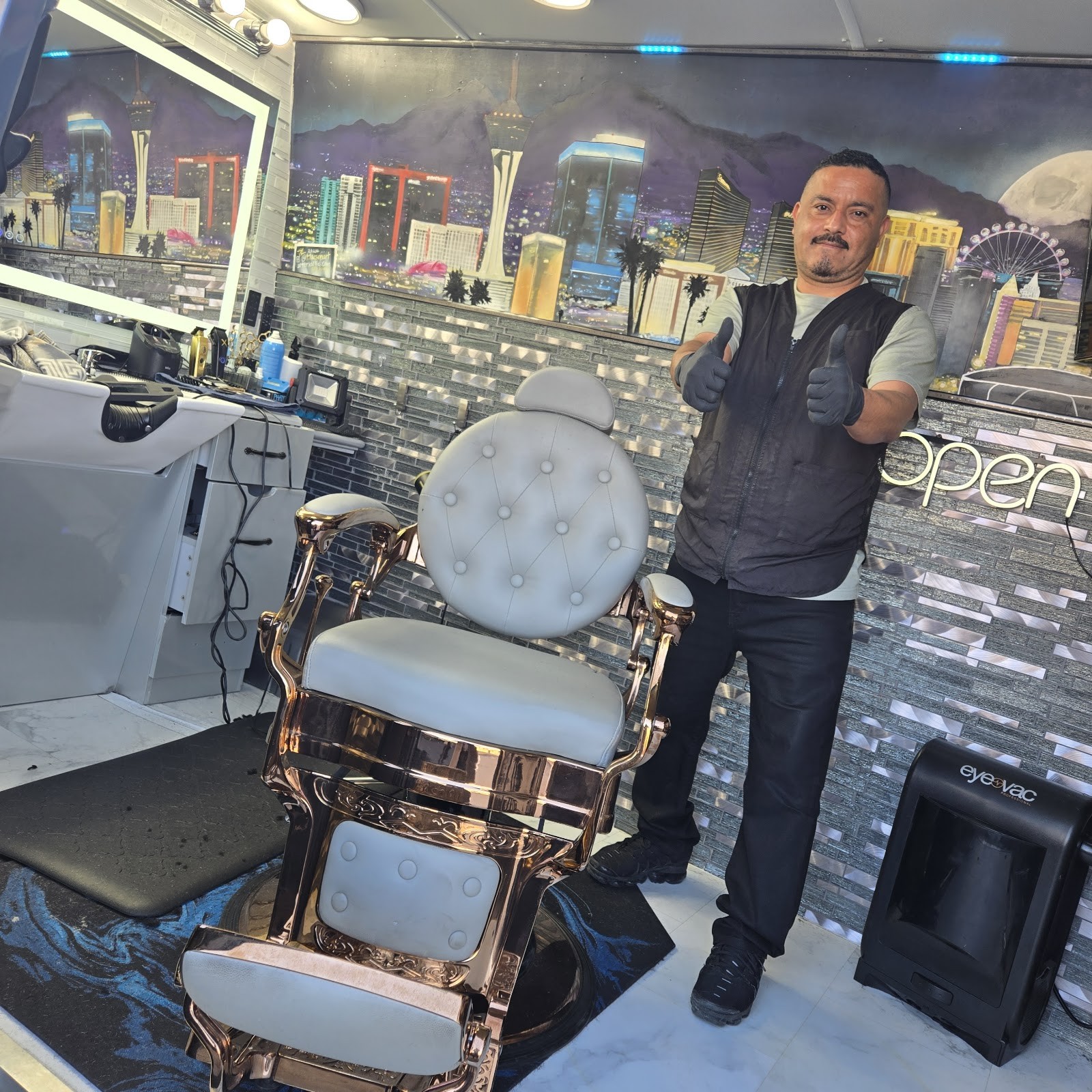 Barber giving a thumbs up next to the gold and white barber chair inside the van