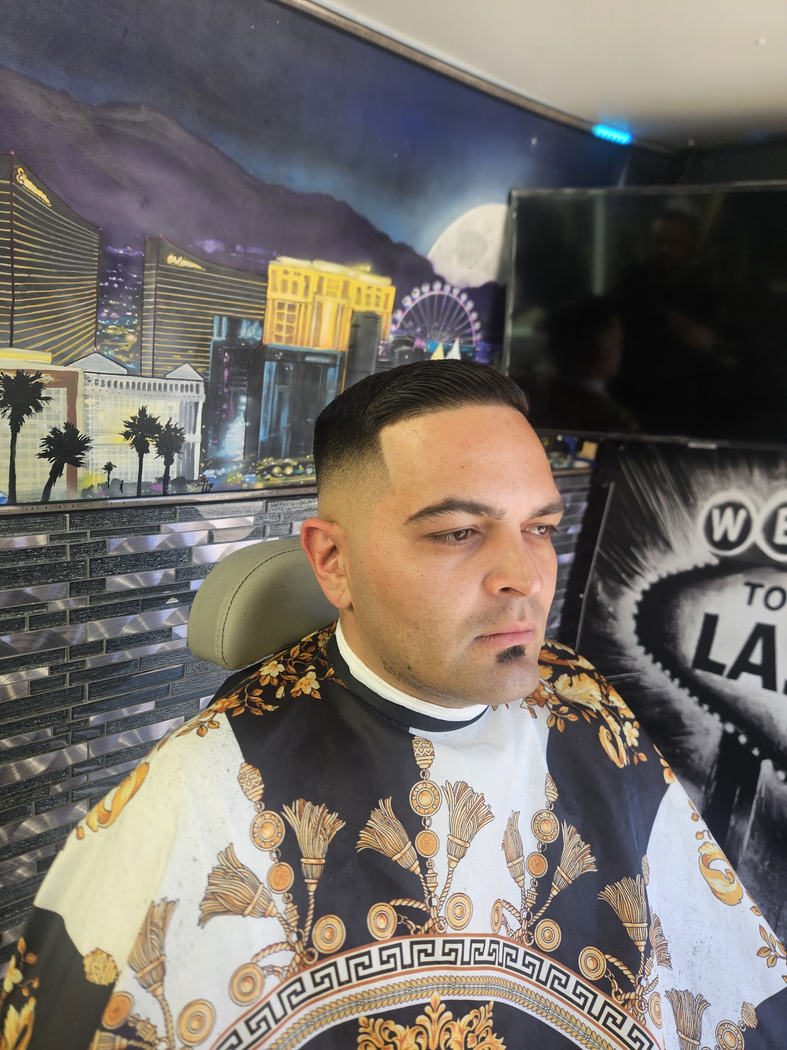 Client with a fresh fade haircut seated in the barber chair with the Vegas skyline mural behind