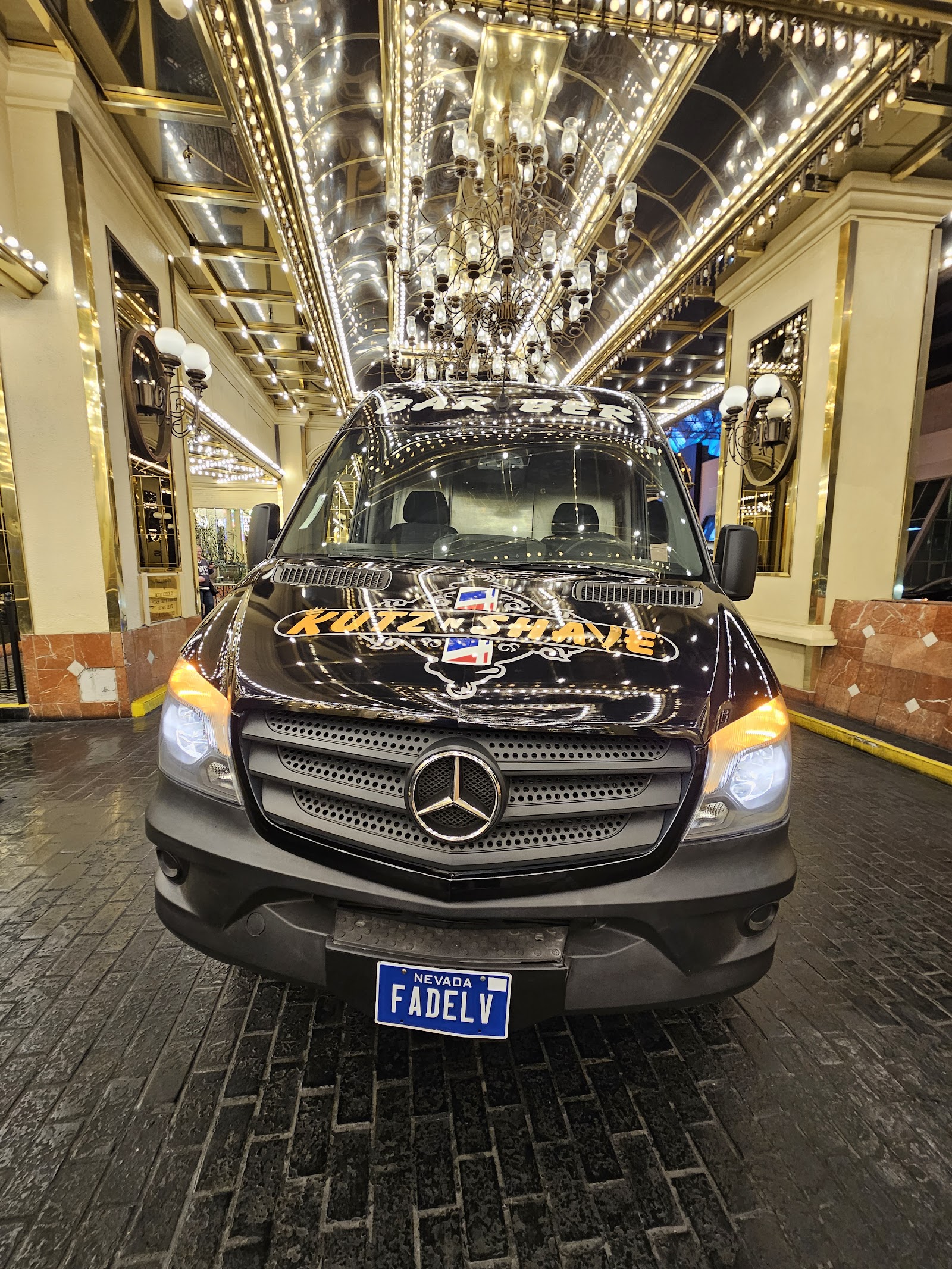 Front view of the black Mercedes Sprinter barber van with 'Kutz N Shave' branding under casino lights